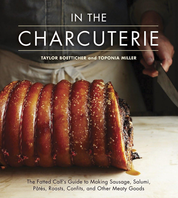 Open charcuterie cookbook by Penguin Random House LLC featuring cheese, meats, and appetizer preparations on a rustic wooden table.