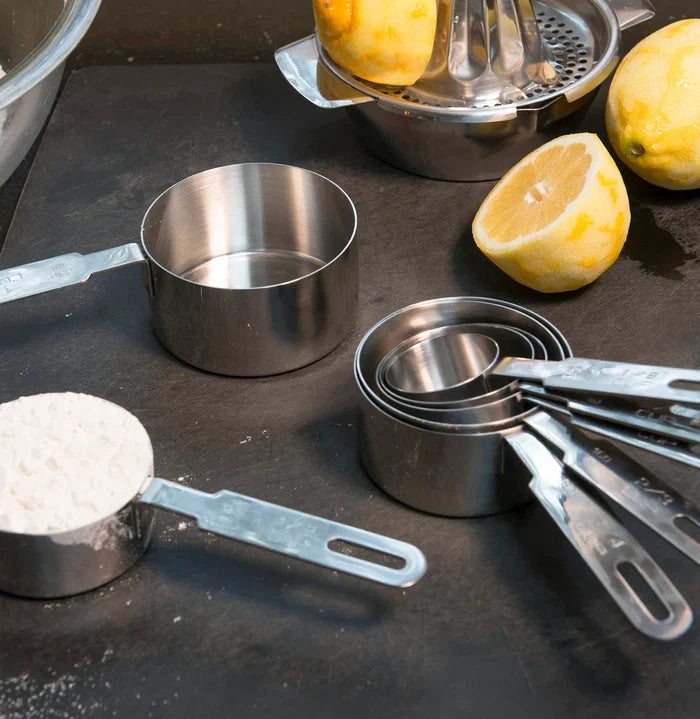 Set of seven RSVP International measuring cups and spoons with bowls, stainless steel kitchen tools for accurate ingredient measurement.