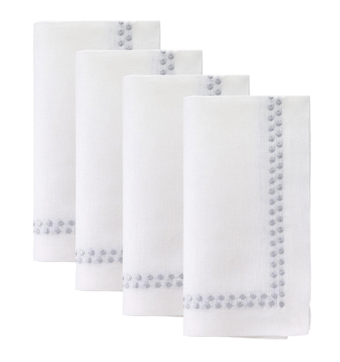 The Bodrum Pearls Napkin Silver Set of 4 features fine linen napkins with embroidered silver dots along two sides, neatly folded and arranged in a staggered row against a white background.
