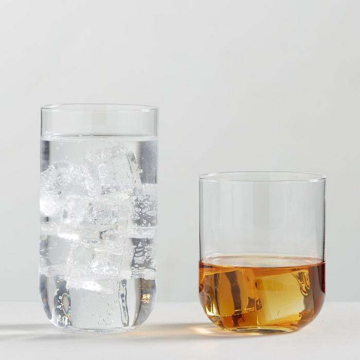 Two clear glasses from the Luigi Bormioli Sublime DOF Set of 4 rest on a light surface—one tall, filled with sparkling water and ice, and one short with an amber drink. Both are dishwasher safe for easy cleaning.