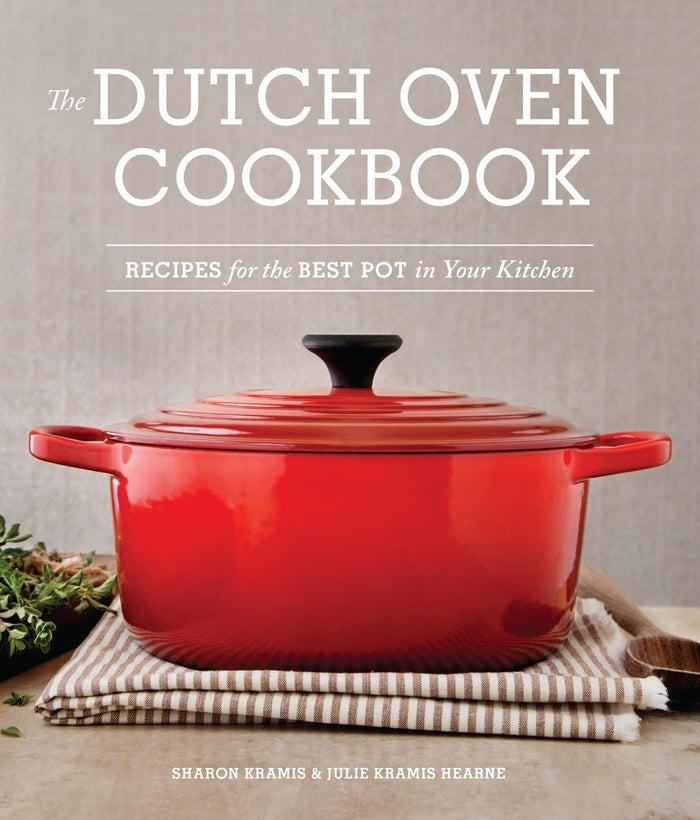 Close-up of a Dutch oven on a stovetop, with a copy of The Dutch Oven Cookbook by Penguin Random House LLC in the background.